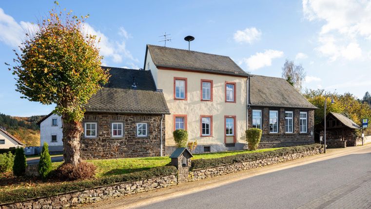 Een groep mensen staat 's nachts langs een straat. Een ridder in een rode mantel rijdt op een paard en praat met de kinderen.