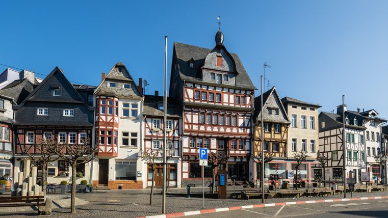 A picturesque old town with historic half-timbered houses. The sky is clear and the street is quiet.