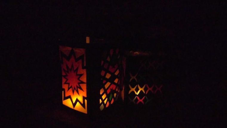 Bunte Laternen leuchten im Dunkeln. Ihre Muster erzeugen ein warmes und einladendes Licht.