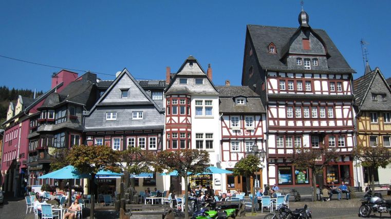 Maisons à colombages colorées dans une ville pittoresque. La rue est équipée de tables et de chaises pour les invités.