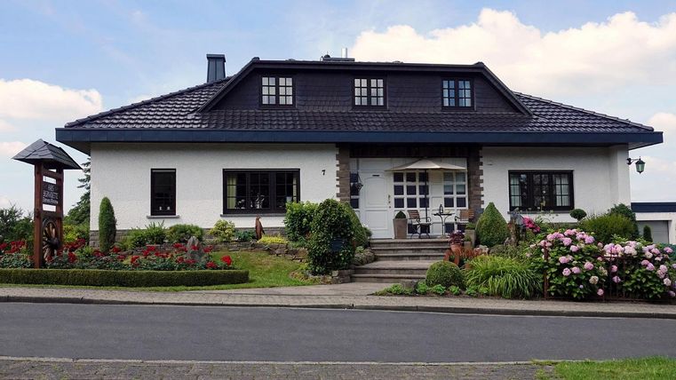 A beautiful house with a well-maintained garden and colorful flowers. The sky is clear and the atmosphere is inviting.