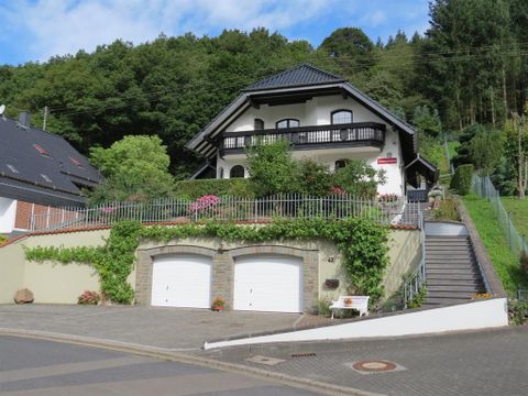 A beautiful house with a well-maintained garden and a driveway. It is located in a quiet, green area.