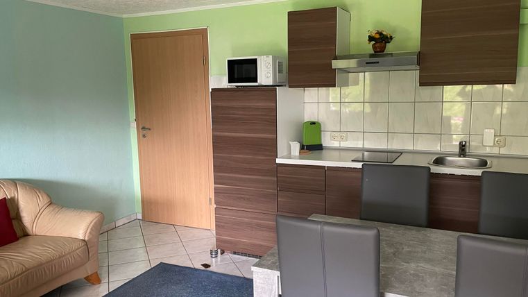 A modern kitchen corner with a dining table and chairs, as well as a cozy seating area. The walls are painted in soft colors and the light is friendly.