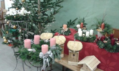 Ein dekorierter Tisch mit Weihnachtskränzen, Kerzen und einem kleinen Baum. Die Umgebung ist festlich geschmückt und in warmen Farben gehalten.