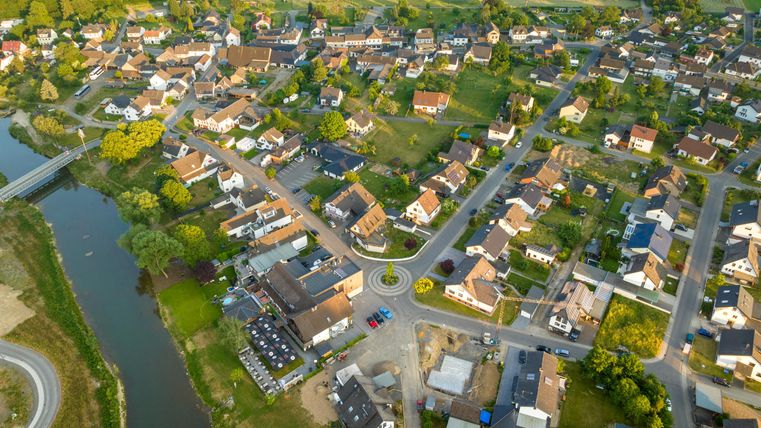 An idyllic, rural community with single-family homes and green fields. A river runs through the landscape and connects the surroundings.
