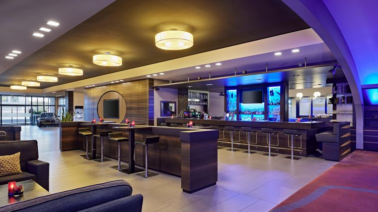 A modern bar with stylish interior and soft lighting. Cozy seating and an inviting atmosphere characterize the space.